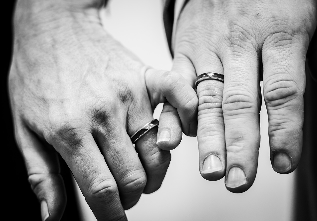 Gros plan sur deux mains de mariés lors d'une cérémonie de mariage en noir et blanc, à Pleyben dans le Finistère en région Bretagne