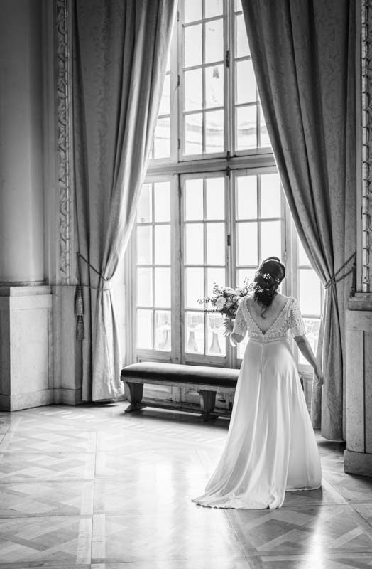 Mariée de dos en noir et blanc face à une fenêtre lumineuse, mairie du 5ème arrondissement de Paris près du Panthéon